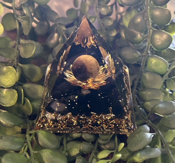 Cette orgonite pyramidale a été fabriqué avec, en son centre, une sphère œil-de-tigre formant la fleur de lotus. Cette même sphère est une protection
